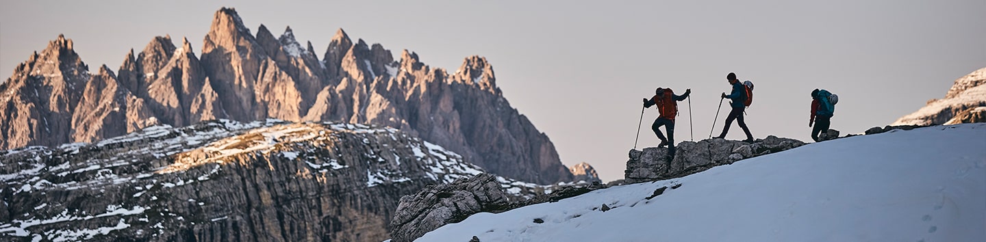 Drei Wanderer im Winter vor einer Berggruppe